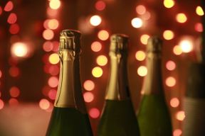 3 Champagne bottles with lights in the background